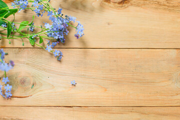 Blue small forget-me-nots flowers on a wooden background. The concept of eco style, natural texture. Space for text. Flatlay