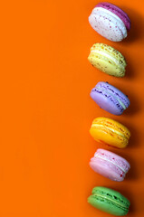 Colorful macaroon desserts on the orange colored background