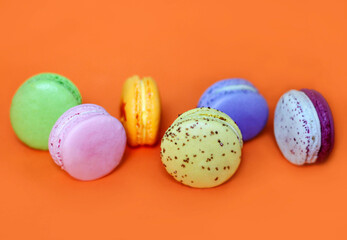 Colorful macaroon desserts on the orange colored background