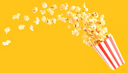 popcorn in classic red and white bucket splashing out of the box in yellow background