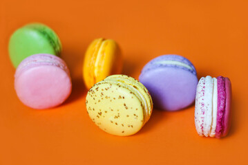 Colorful macaroon desserts on the orange colored background