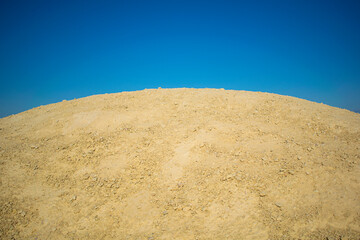 Hill quarry. Sandy mound against the blue sky.