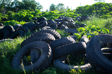 Old, worn, used black tires. The problem of ecology and recycling. Rubber tires thrown in the grass.