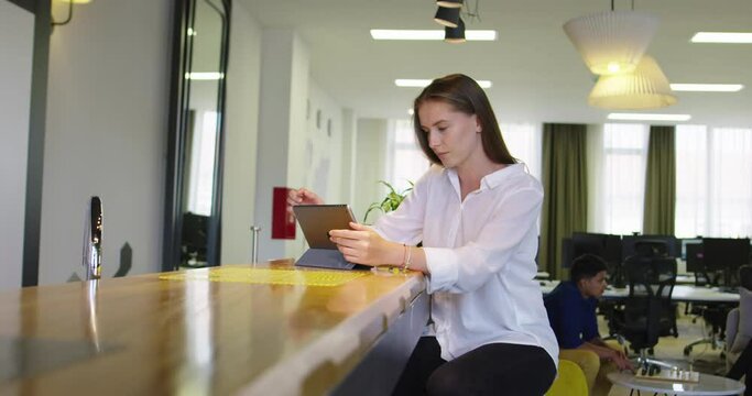 Woman in office kitchen using tablet and working in startup office