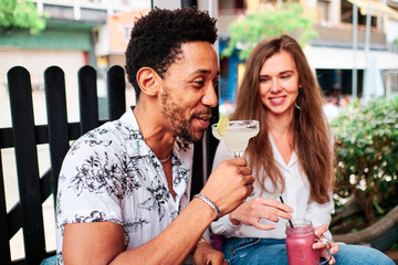 young interracial couple in love drinking a cocktail at the bar in summer