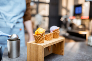 Ice cream in waffle cone with different flavors on the store counter, close-up