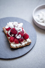 sandwich with raspberries, cream cheese and coconut flakes on marble background with copy space