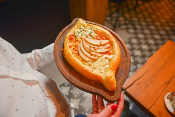 Close up of waiter serving a plate of Khachapuri - hachapuri in Adjarian. Waiter at work. Restaurant service.