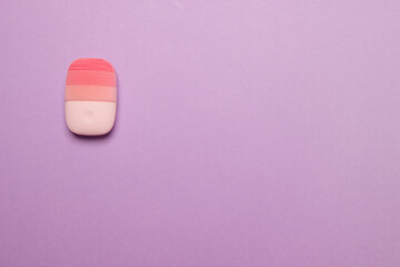 pink electric face massager on pink colored paper background, top view with copy space