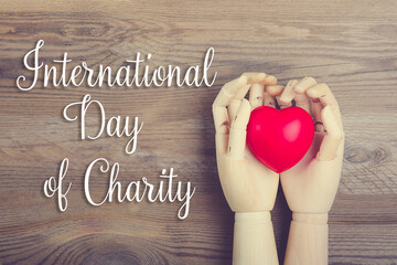 Hand holding red heart on wooden background Top view Flat lay International day of charity concept