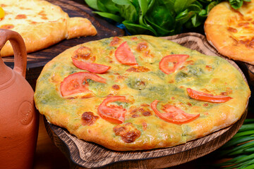 Traditional Georgian Kolkh khachapuri with suluguni and brynza cheese on the table. Khachapuri Megruli. Homemade baking.