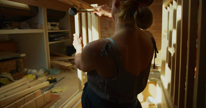 Pregnant woman building a staircase bannister in an attic room