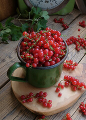 Green enameled mug with red currants on a background of green household weights