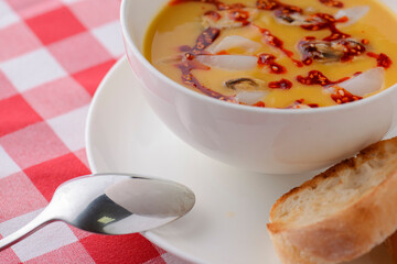 Hot and sour soup with shrimps and clams. Sea food soup with sauce served in a white bowl over light rustic wooden table