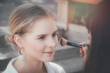 Makeup artist hand working with beautiful young woman,  applying makeup for female model face