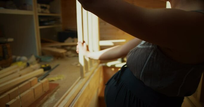 Pregnant woman building a staricase bannister in an attic room