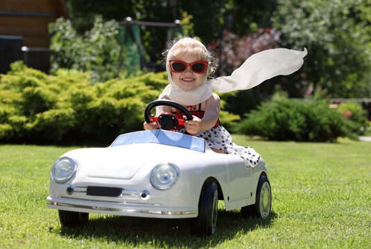 Toddler riding toy car in backyard