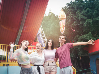 Fototapeta premium Grupa przyjaciół nastolatków spędzających razem czas w parku rozrywki w letni weekend, młoda piękna przyjaciółka spędzająca czas i bawiąca się w parku rozrywki.