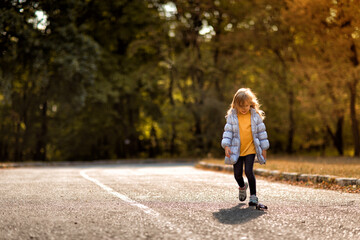 little girl in coat in autumn plays with toy car on remote control in Park. 