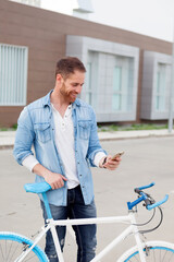 Casual guy next to a vintage bicycle with the mobile wearing denim shirt