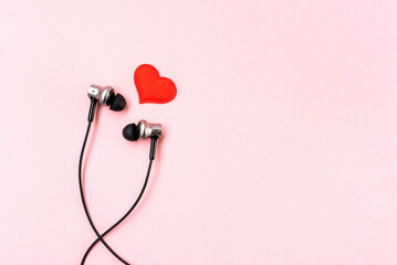 Red heart with music earphones on pink pastel background. Headphones are like a pair of lovers. Valentines Day backdrop. Romantic and love. Minimalist postcard.