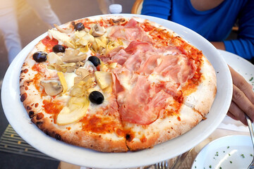 lifestyle photo - pizza topped with smoked bacon and mushroom in traditional italian street restaurant