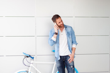 Casual guy next to a vintage bicycle with the mobile