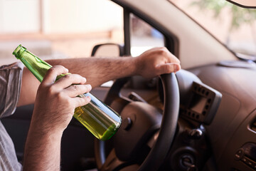 An unrecognizable man drinking beer while driving car. Concepts of driving under the influence, drunk driving or impaired driving