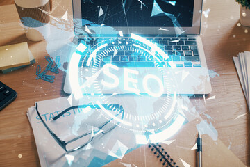 Double exposure of table with computer and seo drawing hologram. Search optimization concept.