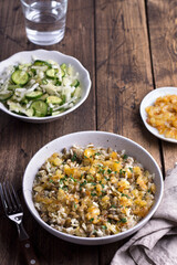 Traditional Middle Eastern dish, Mujadara of lentils, rice and fried onions with a salad of cabbage and cucumbers on wooden table, top view, selective focus, space	