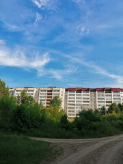 Fototapeta na wymiar view from the forest to a modern residential building under a blue summer sky