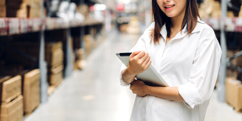 Portrait of manager worker woman standing and order details on tablet computer for checking goods and supplies on shelves with goods background in warehouse.logistic and business export