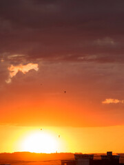 Natural sunset sunrise over the city and meadow. Bright dramatic sky and dark earth, beautiful clouds. Dawn Sunrise. The sun over the horizon, horizon. Warm colors. Beautiful sky.