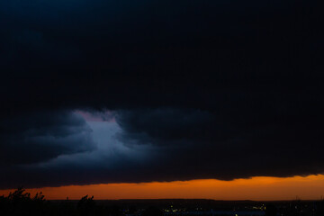 Black thunderclouds at sunset. Bright orange sunset and dark clouds. Storm sky