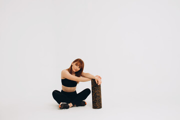 Obraz premium Athlete girl stretching her joints. Photo of young european girl doing exercises on white background. Sport