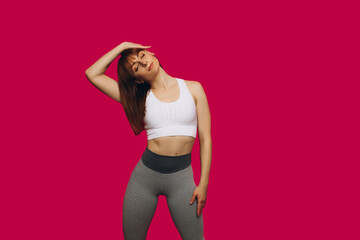Girl performs fitness exercises on isolated pink background. Girl playing sports. Young girl performs stretching exercises. Sports girl. Place for an inscription.