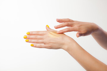 Female hands on a white background. Cream, gliter yellow moose on the skin.
