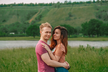 A married young happy couple a man and a woman fool around and hug against the background of a natural landscape with mountains and a lake