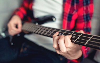 Teenage boy plays bass at home, selective focus