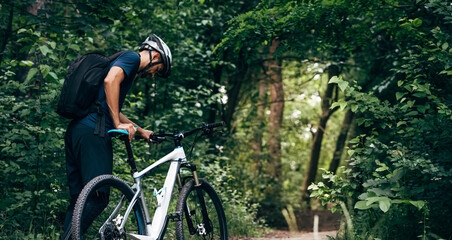 Rear view of professional male cyclist cycling on mountain road on nature background. Male bicyclist riding a bike in the forest outdoor.