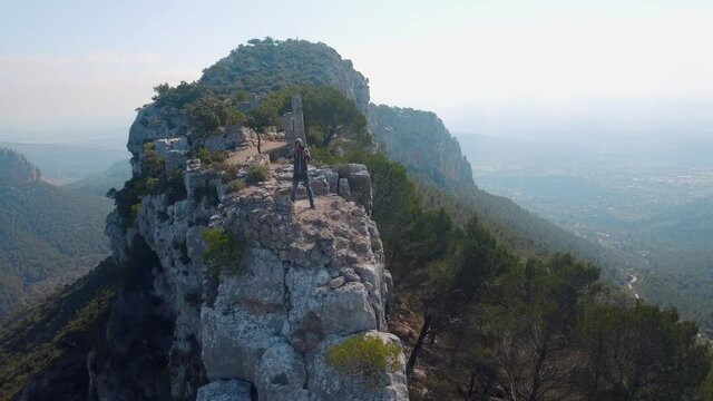 Aerial shot in 4k of a photographer standing on a mountains and takes a picture of a breathtaking landscape.