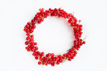 Fresh, ripe red currants laid out in the shape of a ring on a white background
