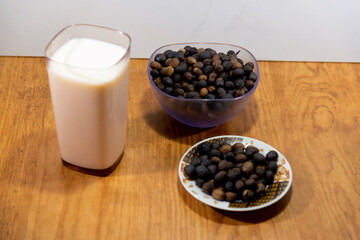 Glass with milk along with roasted coffee beans.