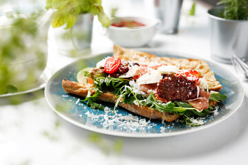 Sandwich with ripening ham, Parmesan cheese, sun-dried tomatoes, green salad.