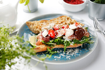 Italian breakfast, bread with ripening ham, Parmesan cheese, dried tomatoes, green lettuce.