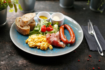 Continental breakfast, scrambled eggs, fried sausage, bacon and vegetable salad. Ready dish served in a hot pan. Suggestion of serving a dish on a plate. food background