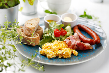 Continental breakfast, scrambled eggs, fried sausage, bacon and vegetable salad. Ready dish served in a hot pan. Suggestion of serving a dish on a plate. food background