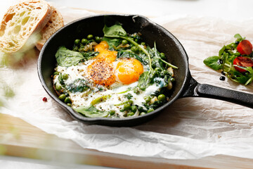 Eggs baked with green peas and spinach. Ready dish served in a hot pan. Suggestion of serving the dish. food background