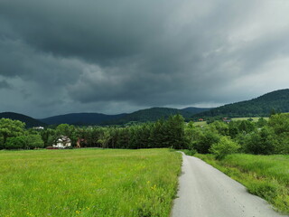 Poland Low Beskids Wysowa Zdroj. Stormy clouds over a country road.