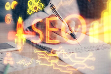 Multi exposure of woman's hands making notes with SEO icon. Concept of Search engine optimization